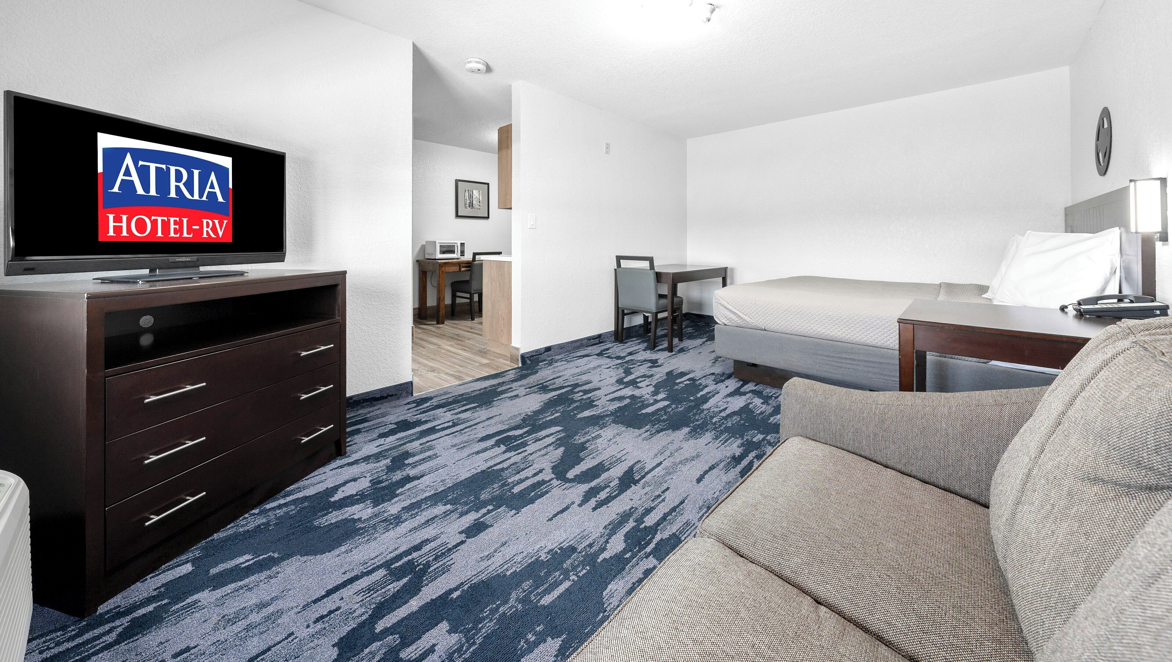 Una habitación de hotel con televisión, cama, escritorio y silla.