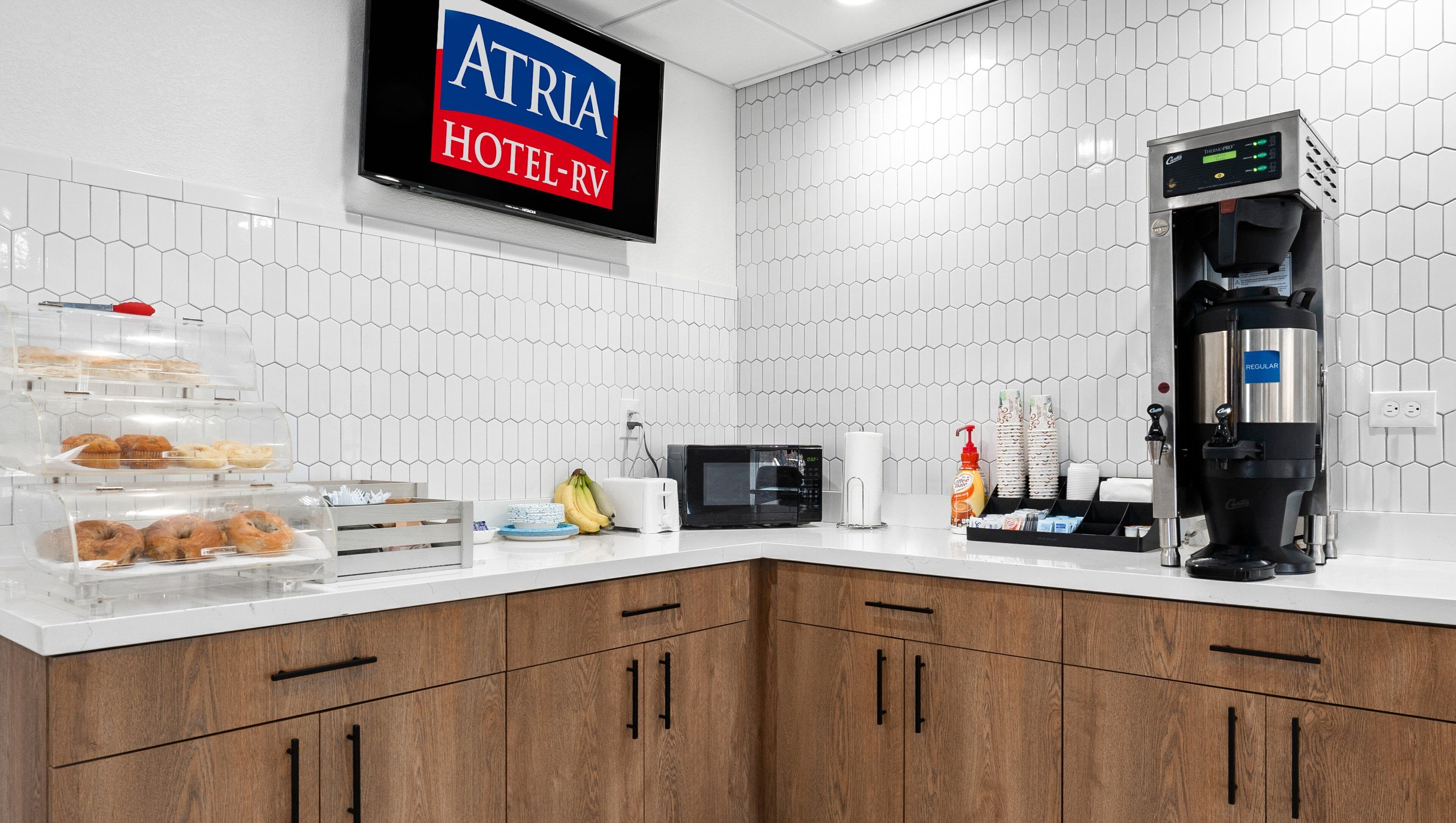 Cocina de hotel con cafetera, microondas y barra de desayuno.