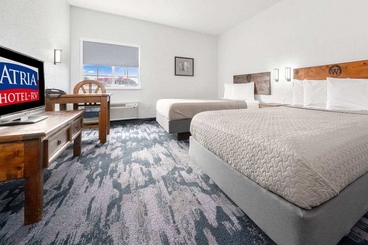 A hotel room with a bed, two bedside tables, a desk with a chair, a TV, and a window with a view.