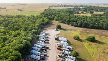 An aerial view of a campground with RVs parked in rows, surrounded by dense forest.