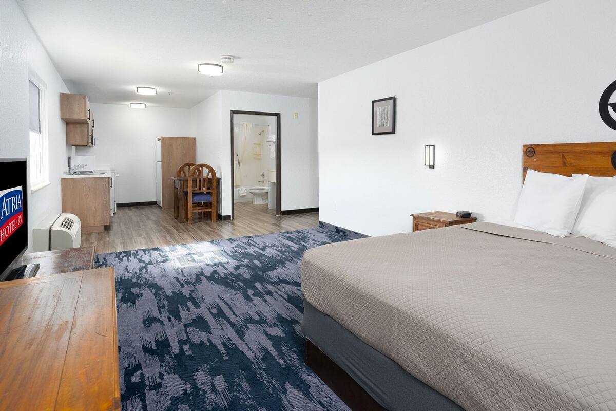 A hotel room with a bed, a desk, a chair, a wardrobe, a bathroom, and a television.