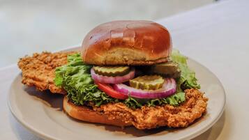 A plate with a sandwich, lettuce, tomato, onion, and pickles.