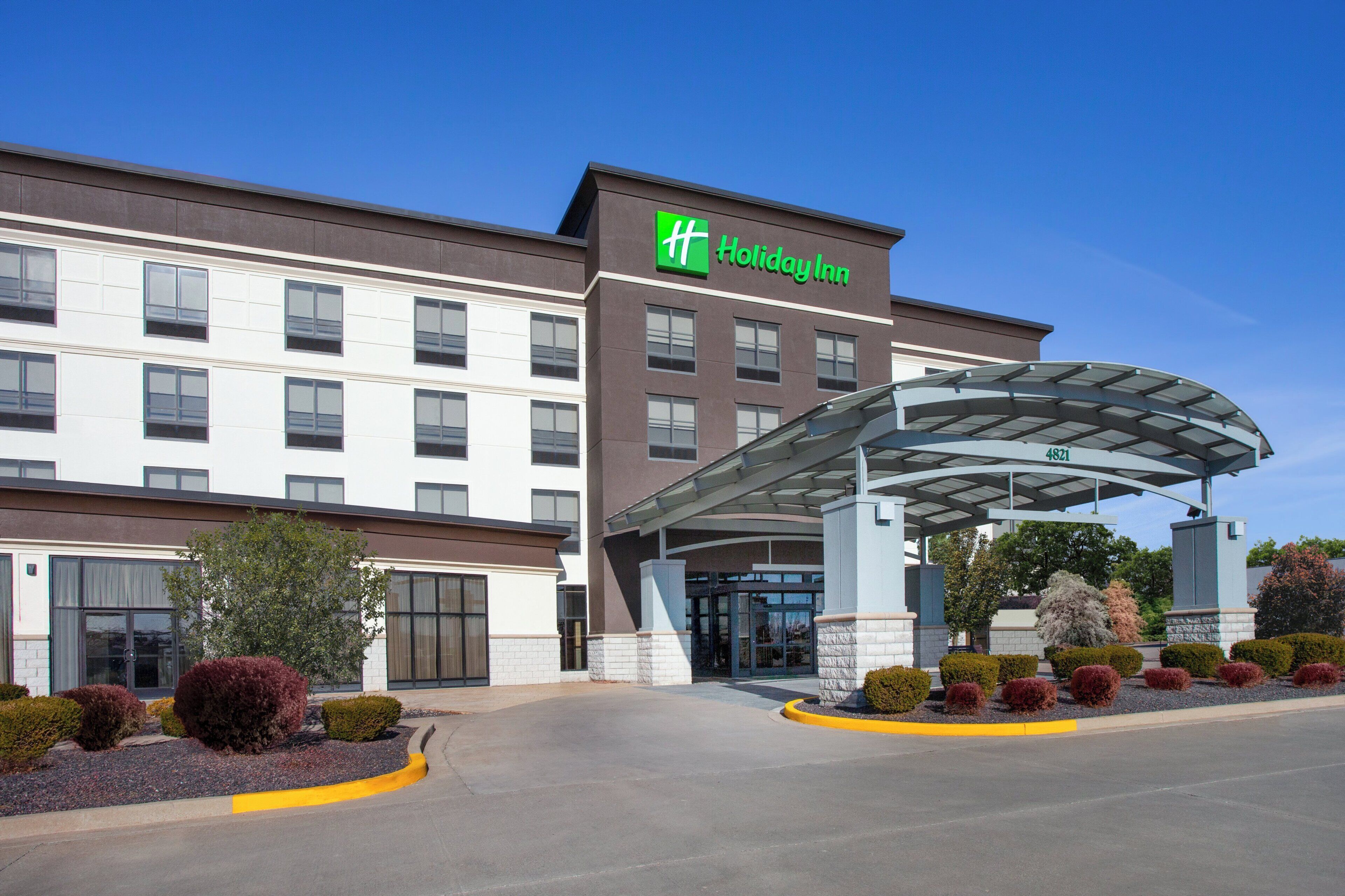 A Holiday Inn hotel with a modern design, featuring a covered entrance and landscaped areas.