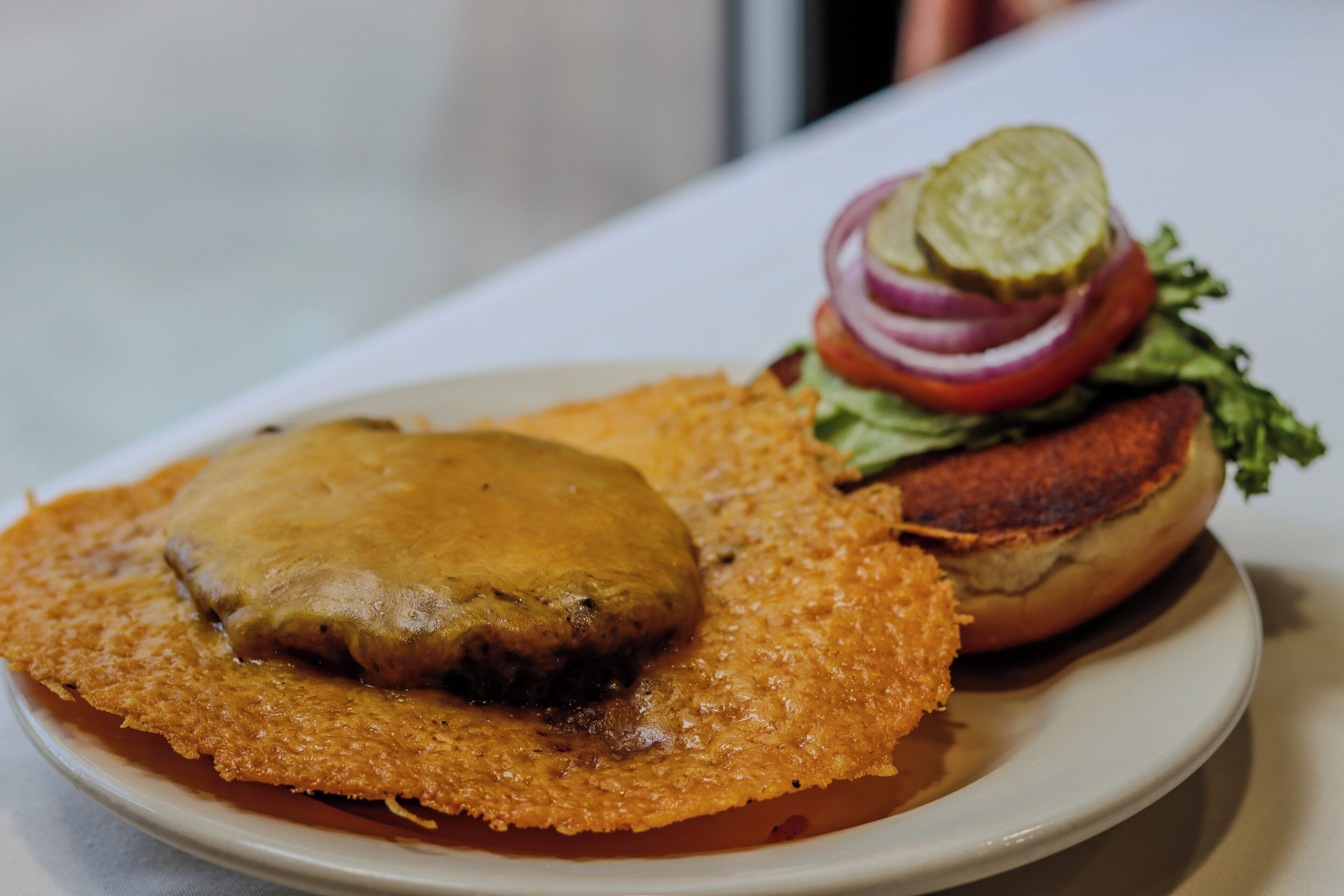 A plate with a fried patty and a burger with lettuce and onion.