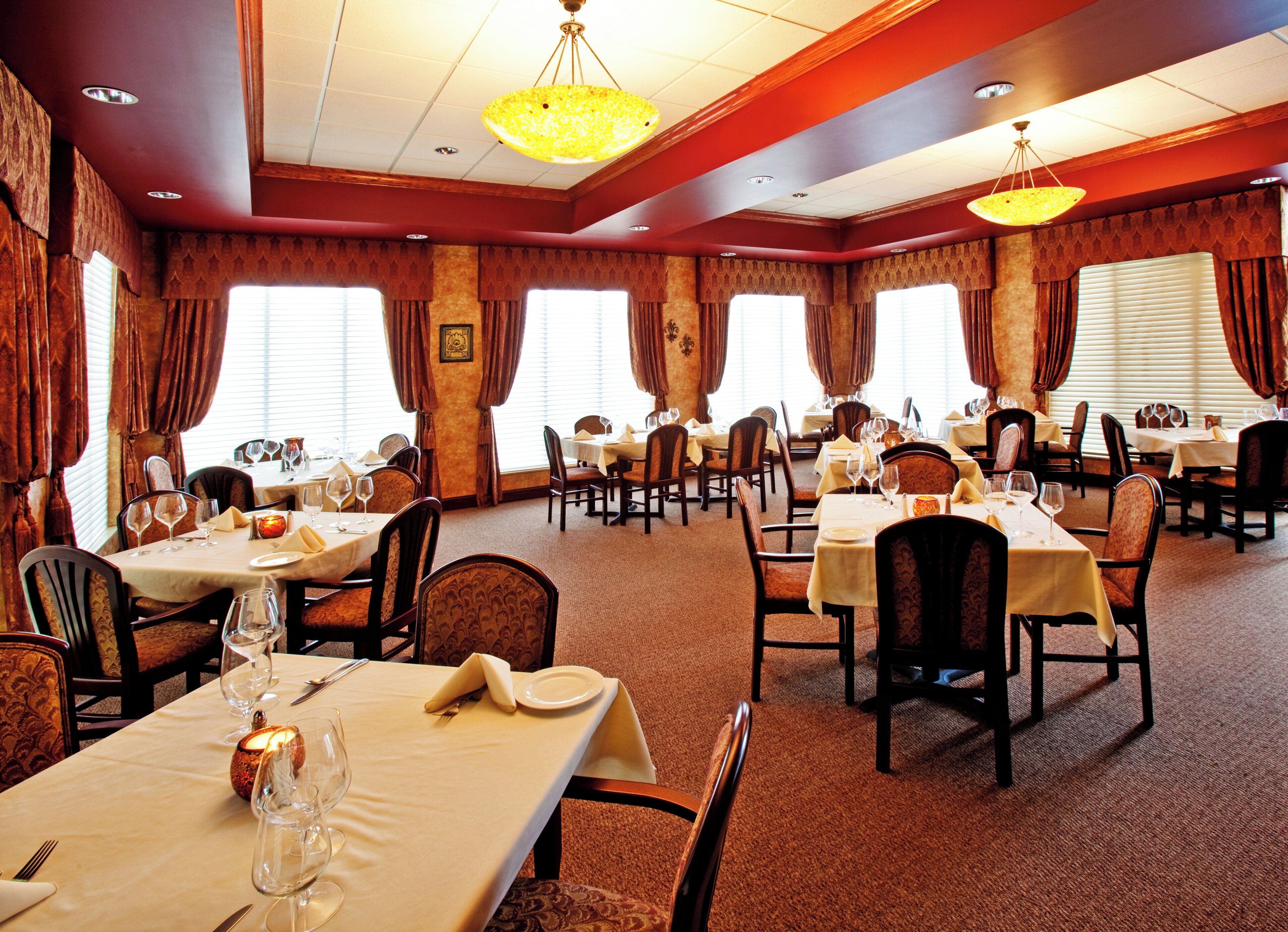 A restaurant with multiple tables set for dining, featuring a carpeted floor and classic decor.