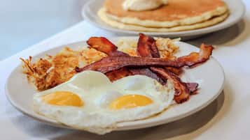 Un plato de desayuno con huevos, tocino y patatas ralladas.