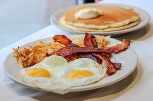 Un plato de desayuno con huevos, tocino y patatas ralladas.