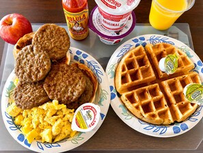 A breakfast tray with sausage patties, scrambled eggs, waffles, and condiments. - Depot Inn and Suites (La Plata)