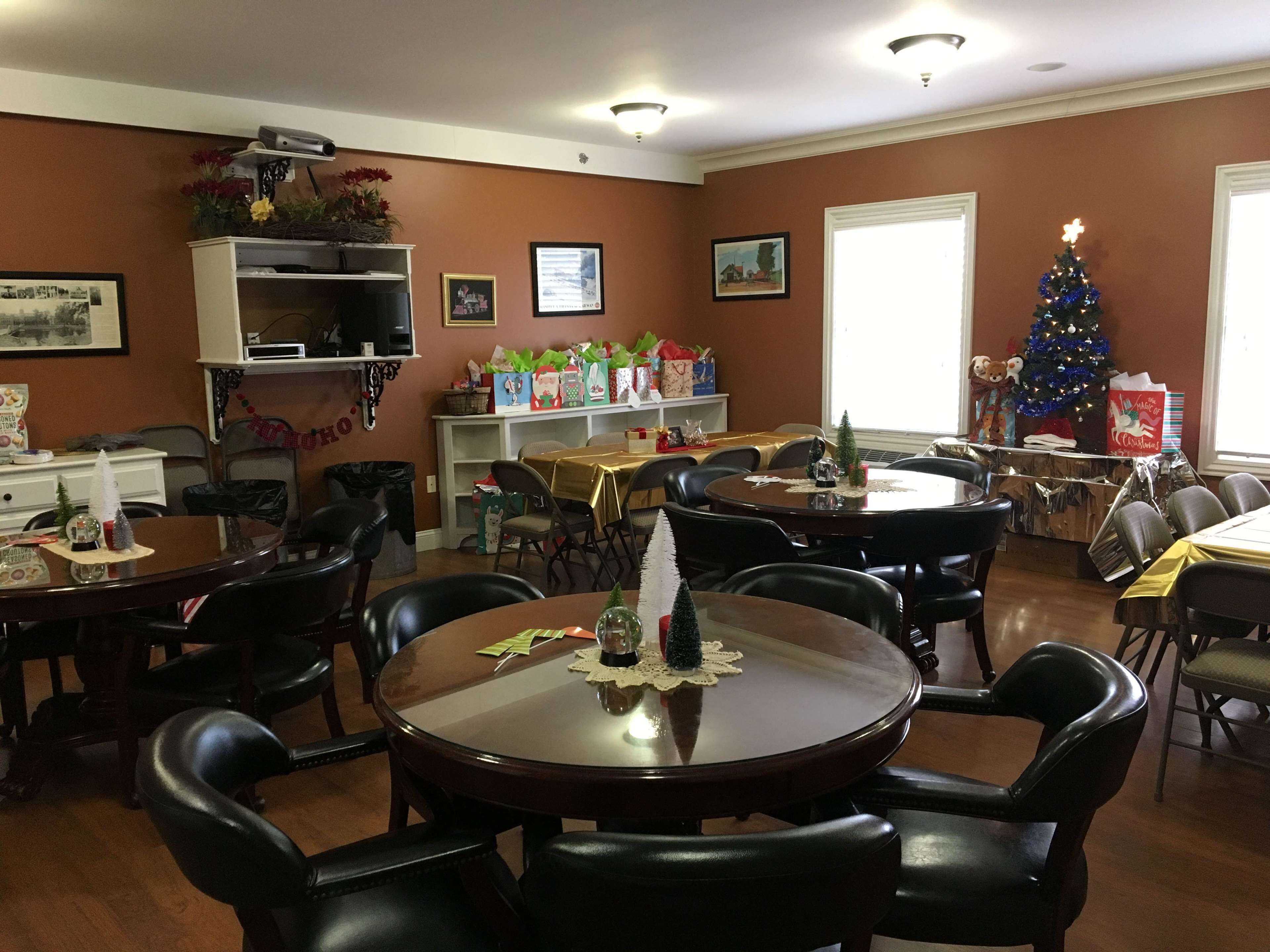A dining area with multiple tables and chairs, a Christmas tree, and holiday decorations.
