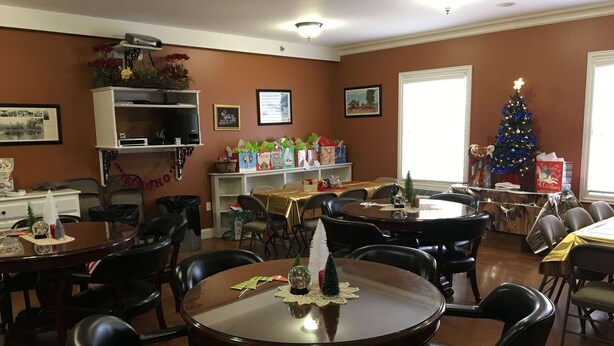 A dining area with multiple tables and chairs, a Christmas tree, and holiday decorations. - Depot Inn and Suites (La Plata)