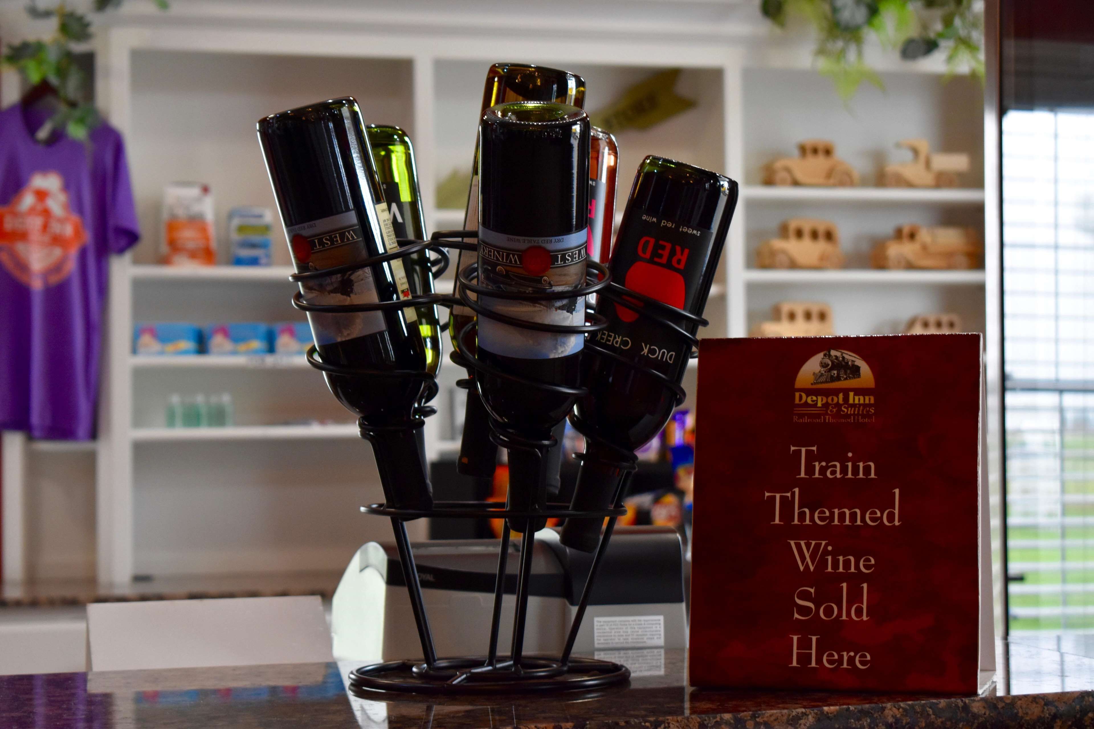 Un présentoir à vin avec de nombreuses bouteilles et une pancarte indiquant : « Vins sur le thème du train en vente ici ».