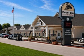 A train-themed hotel with a clock, a sign for themed rooms, and a flag. - Depot Inn and Suites (La Plata)
