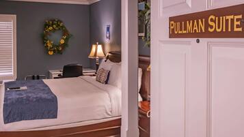 A Pullman Suite with a bed, a desk, a lamp, and a wardrobe.