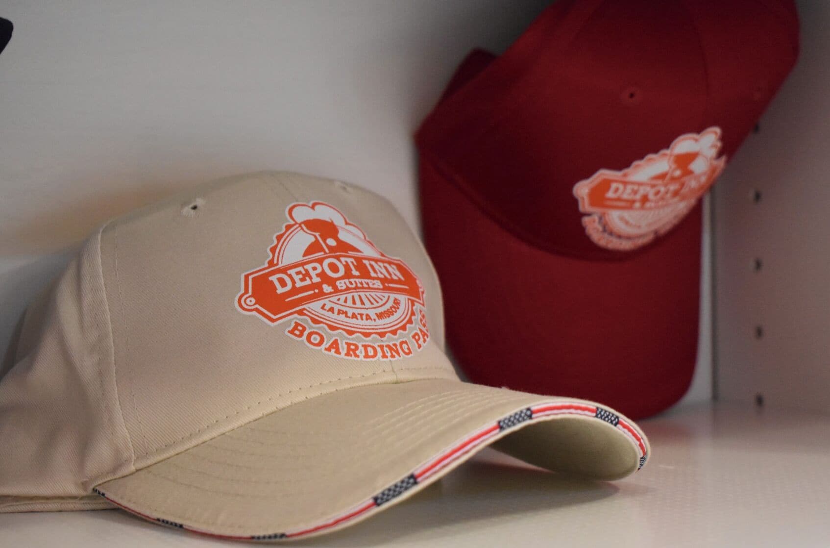 A beige cap with a logo and a red cap with a logo.