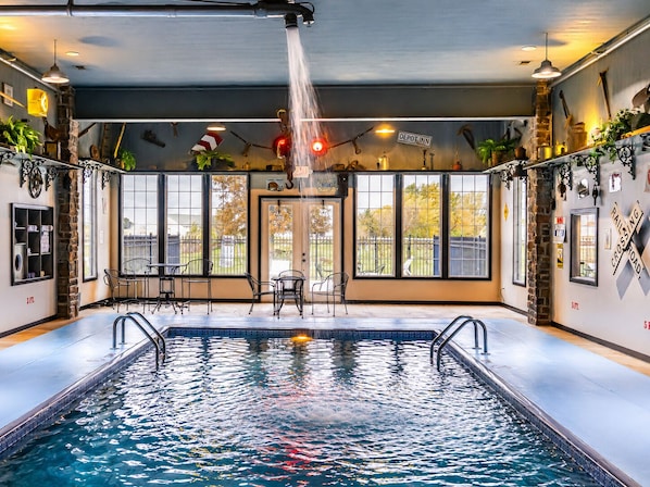 Una piscina interior con vistas al exterior, un cartel que dice 'Depot Inn' y un letrero de 'PASO A NIVEL' en la pared.