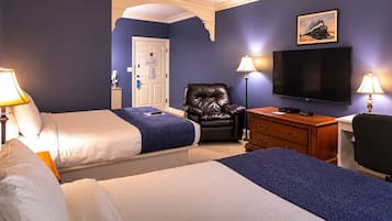 Habitación de hotel con dos camas, un escritorio con silla, una televisión y un sillón de cuero.