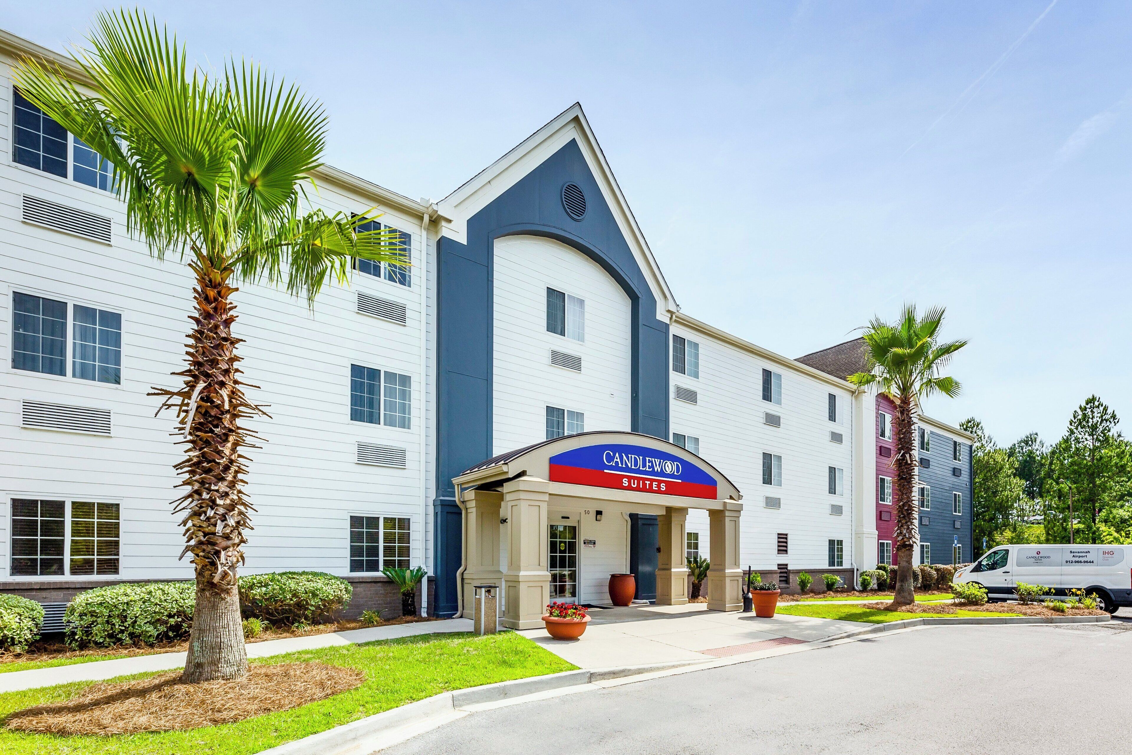 A hotel with a modern design, featuring a prominent entrance with a blue and red sign.