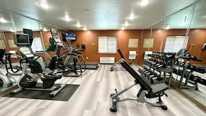 Ett gym med löpband, crosstrainers och träningsbänkar för styrketräning.