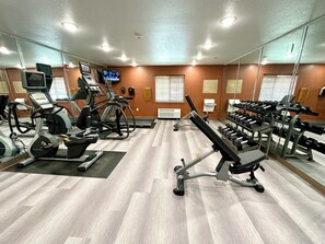 Un gimnasio con cintas de correr, elípticas y bancos de pesas.