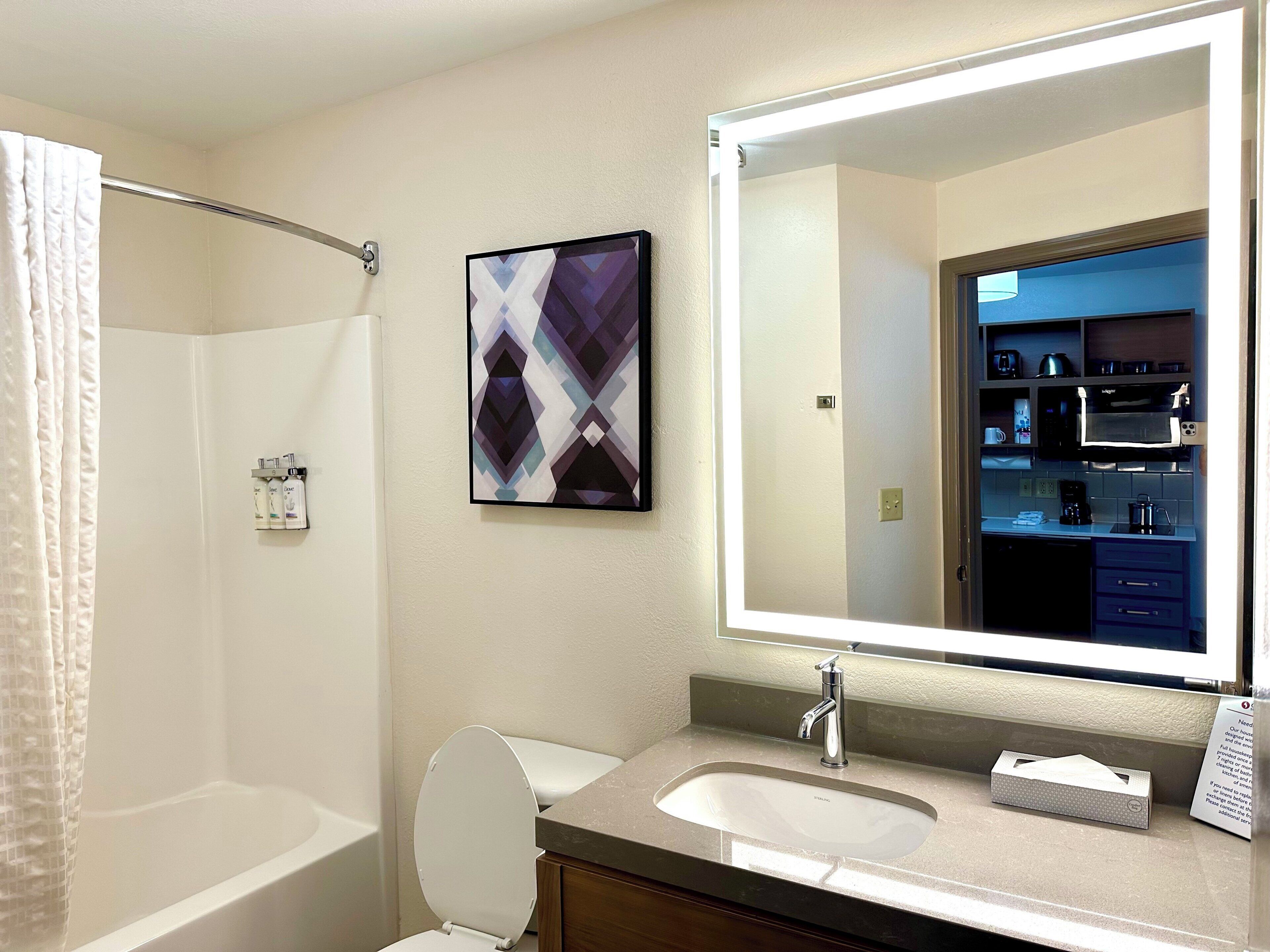 Une salle de bain avec une baignoire, des toilettes, un lavabo et un grand miroir.