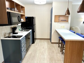 Una cocina compacta equipada con microondas, refrigerador y cafetera.