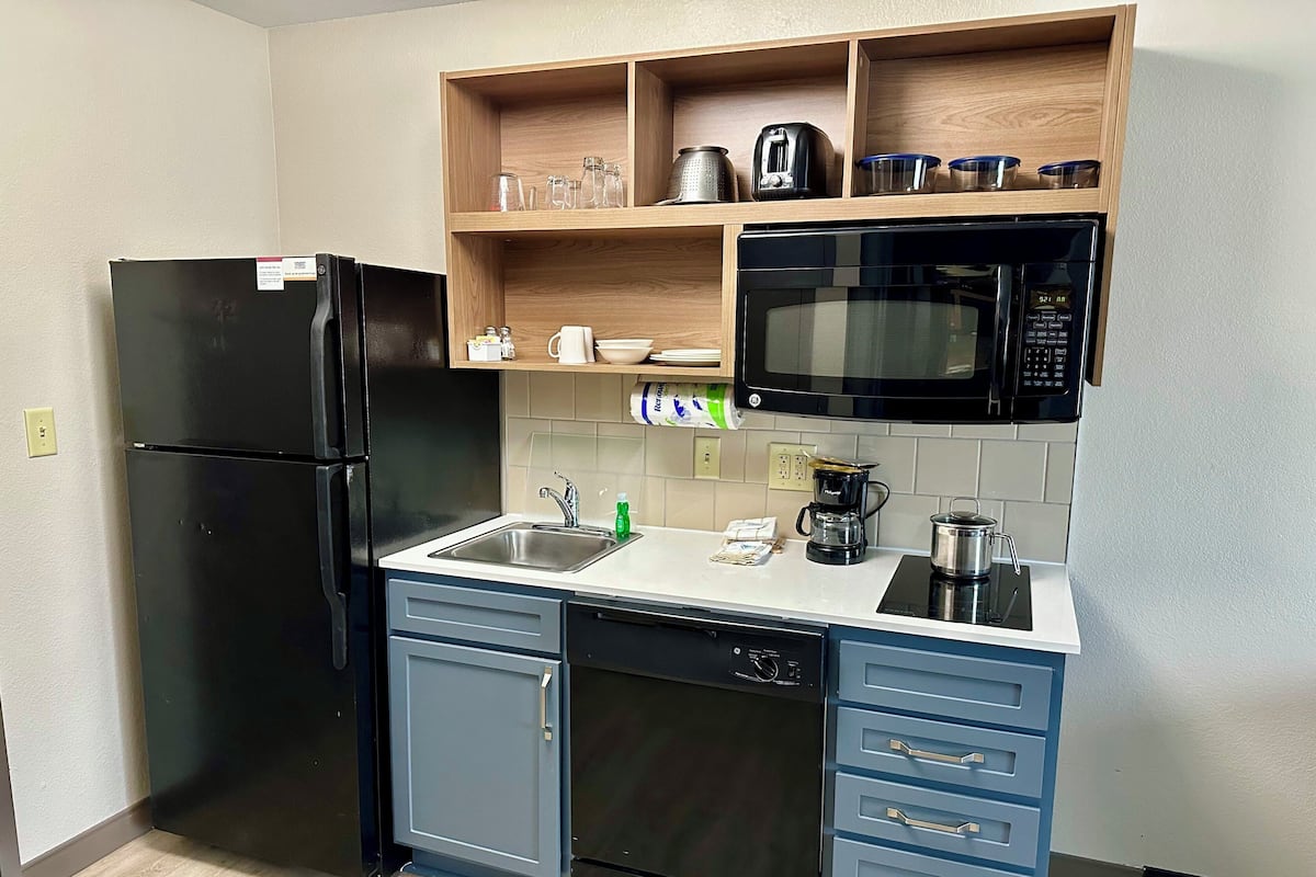 A compact kitchen with a black refrigerator, a microwave, a coffee maker, and a dishwasher.