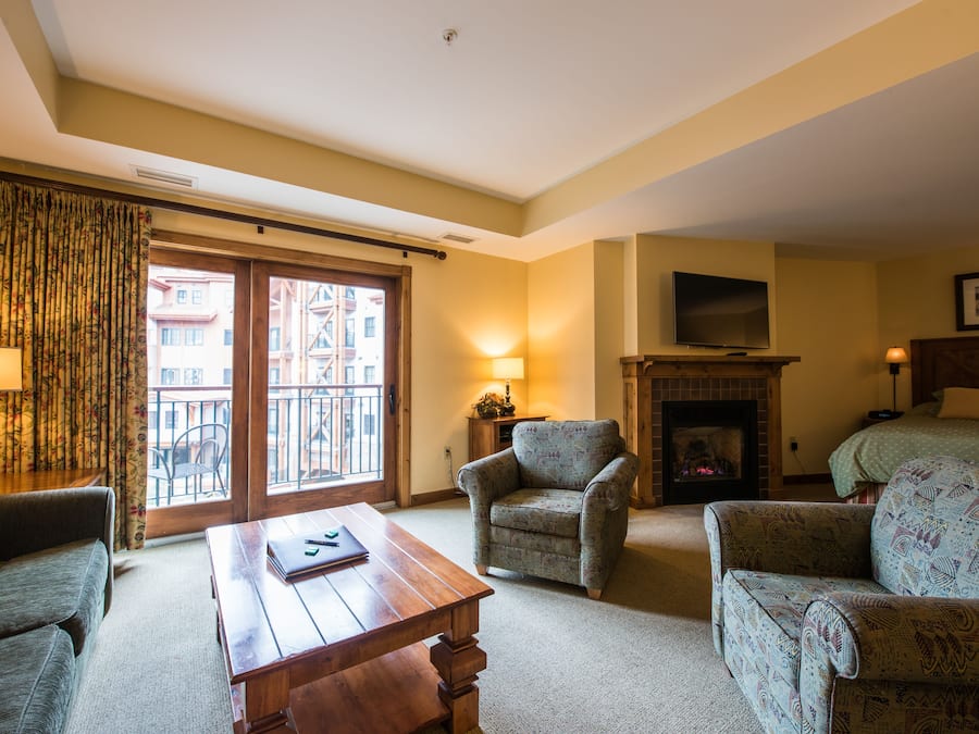Een gezellige woonkamer met een open haard, een televisie en een balkon met gordijnen.