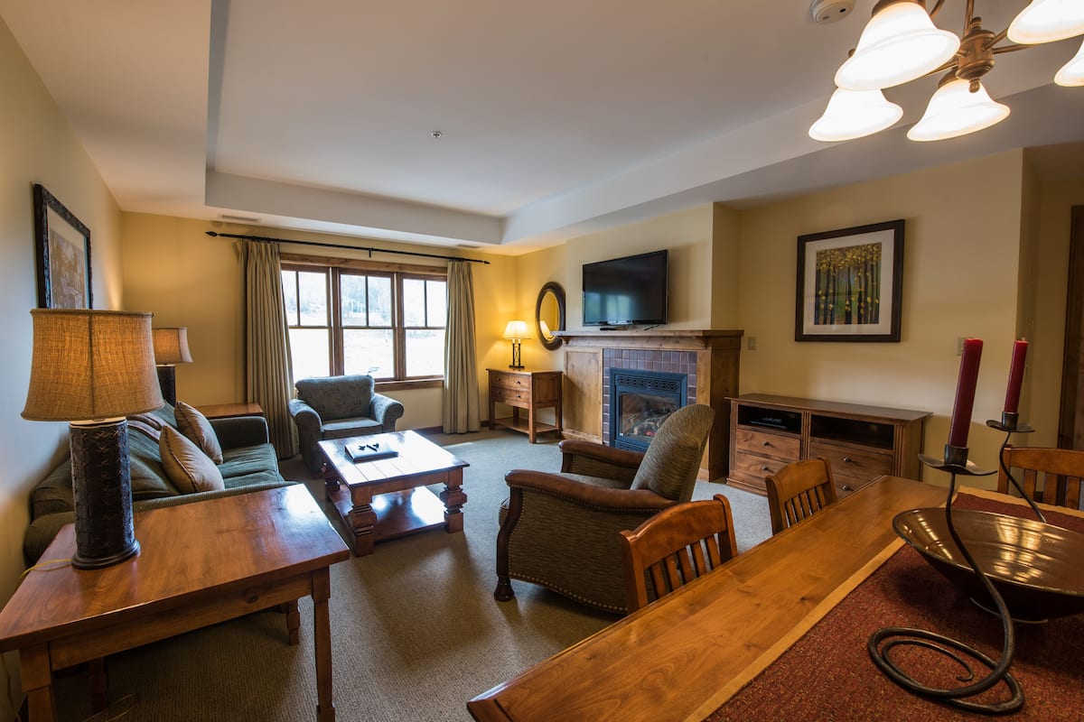 A living room with a fireplace, a television, and a dining area.