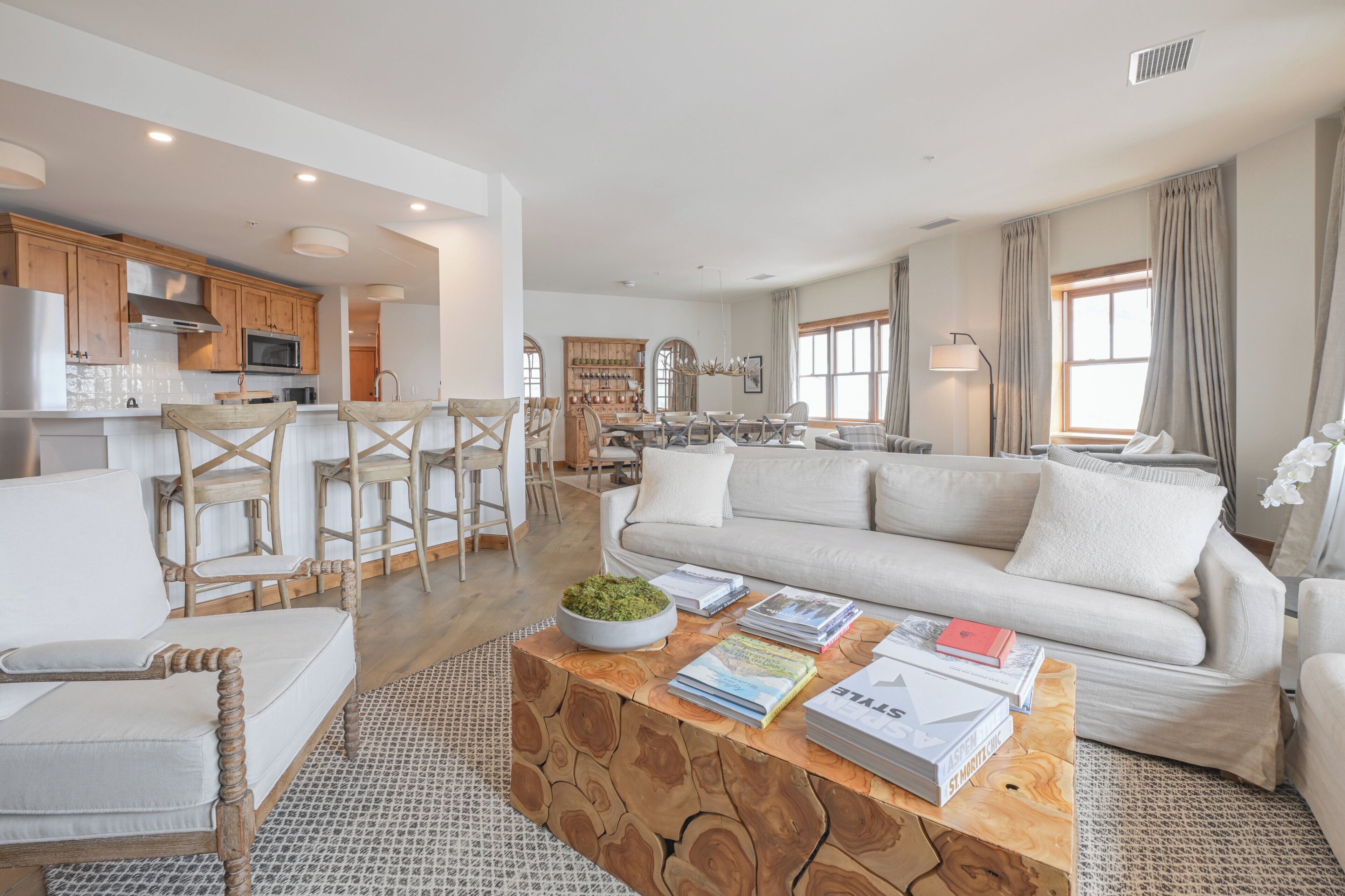 A spacious living area with a large sofa, wooden coffee table, and a kitchen in the background.