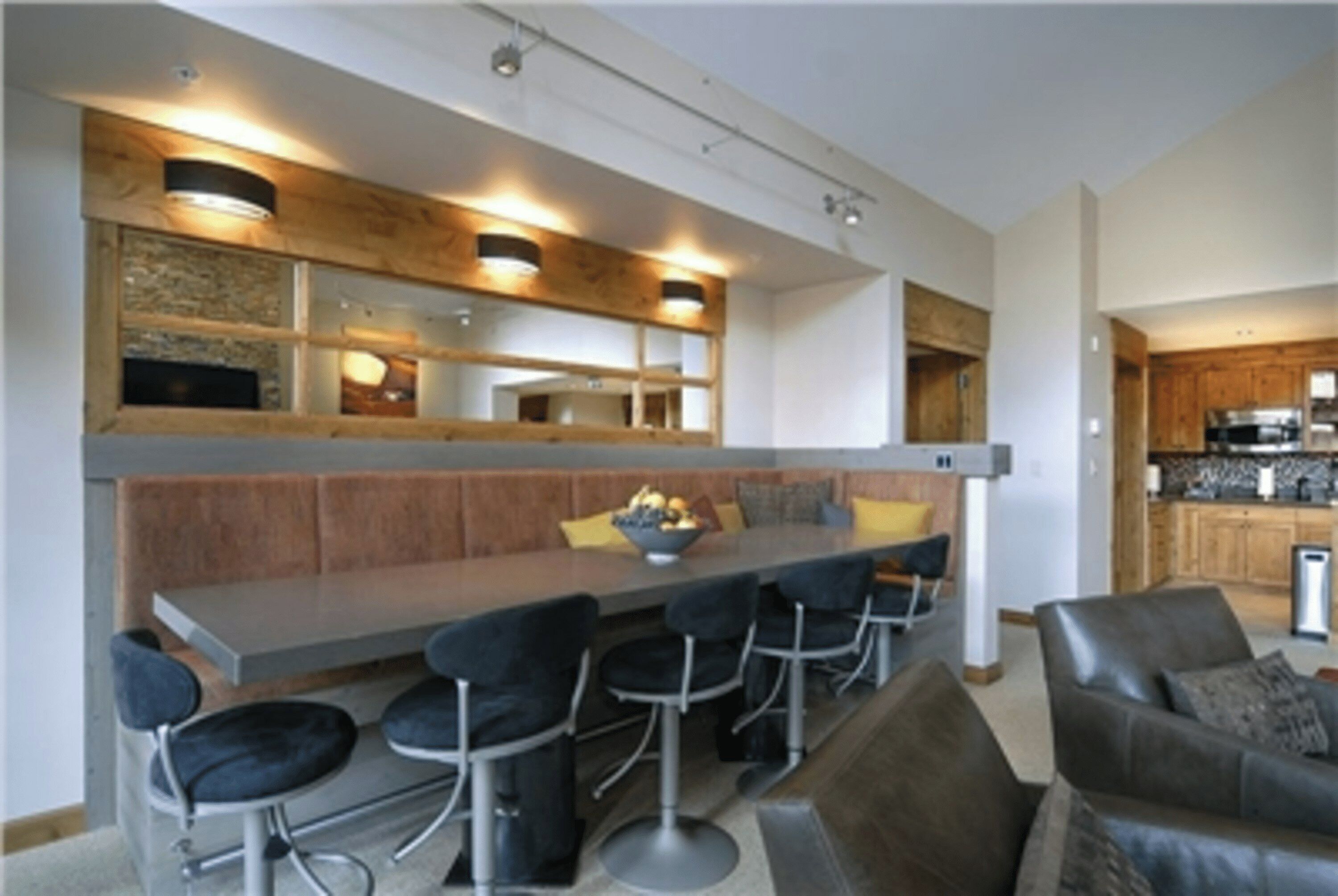 Una cocina moderna con una isla central, taburetes de bar y una zona de estar con sofá y sillas.