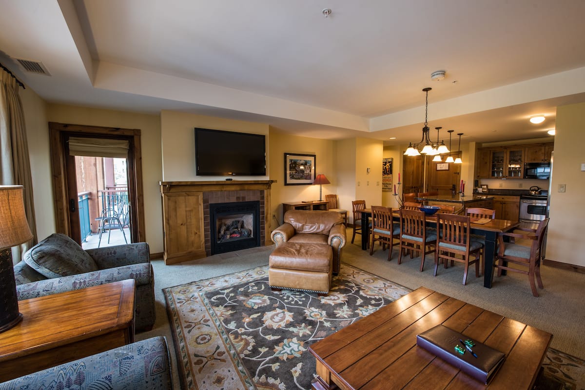 A living room with a fireplace, a television, and a dining area with wooden furniture.