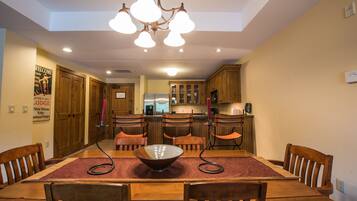 Un comedor con mesa de madera, sillas y una lámpara de araña.