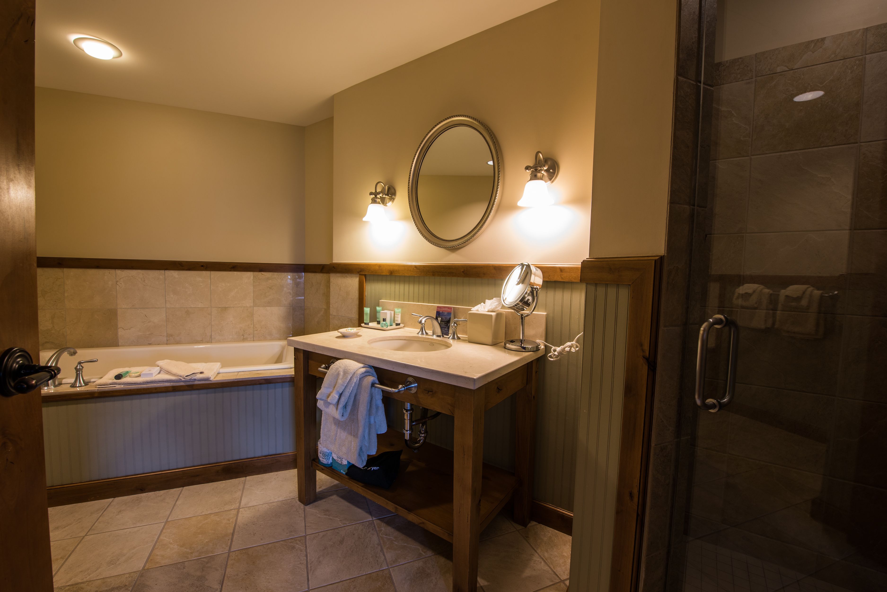 A bathroom with a bathtub, sink, mirror, and shower.