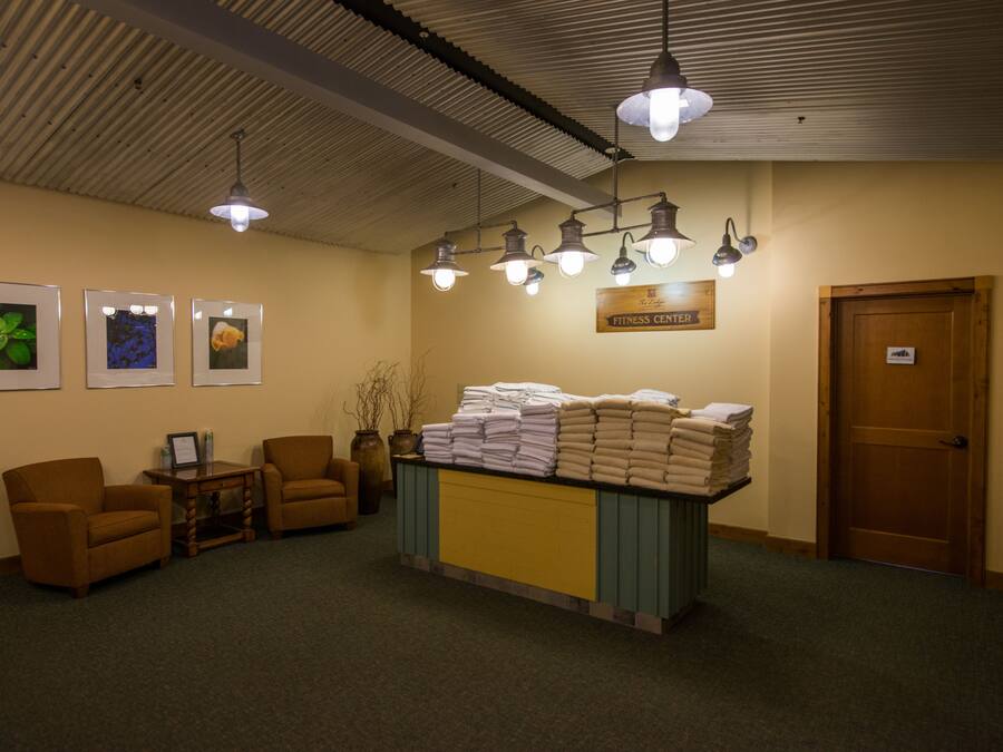 A reception area with a desk, chairs, framed pictures, and a sign indicating a fitness center.