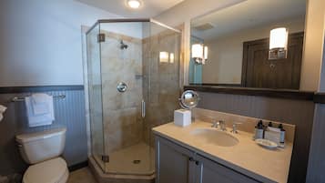 Un baño moderno con ducha de vidrio, inodoro y lavamanos con artículos de tocador.