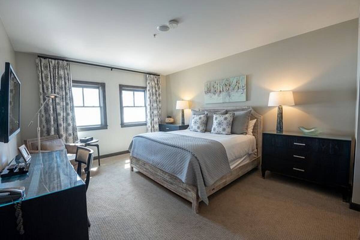 A bedroom with a bed, bedside tables, a desk, and a chair.