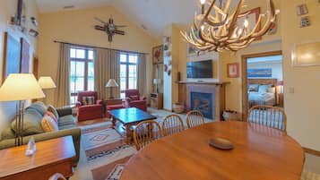 A spacious living room with a large wooden dining table, comfortable seating, a fireplace, and a television.