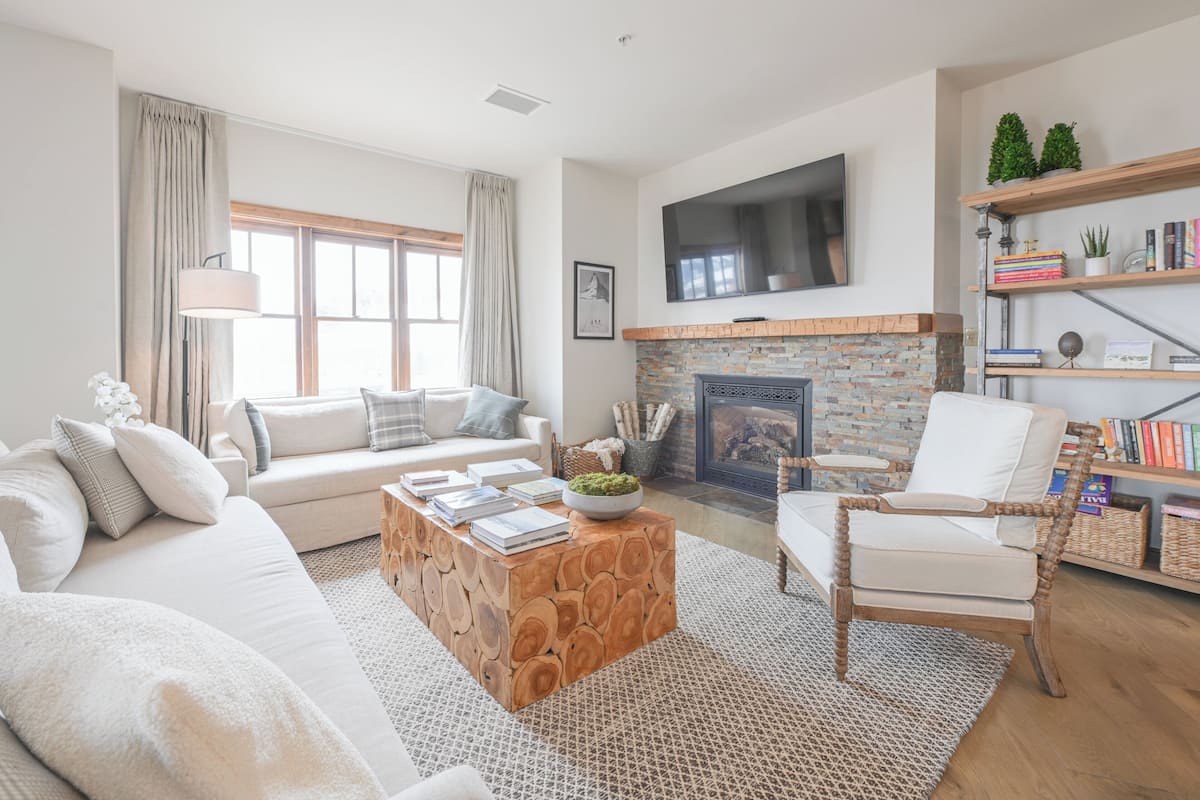 A modern living room with a fireplace, a sofa, a coffee table, and a bookshelf.