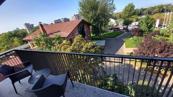 Un balcó amb seients exteriors, vista d'un hotel amb teulada vermella i vegetació circumdant.