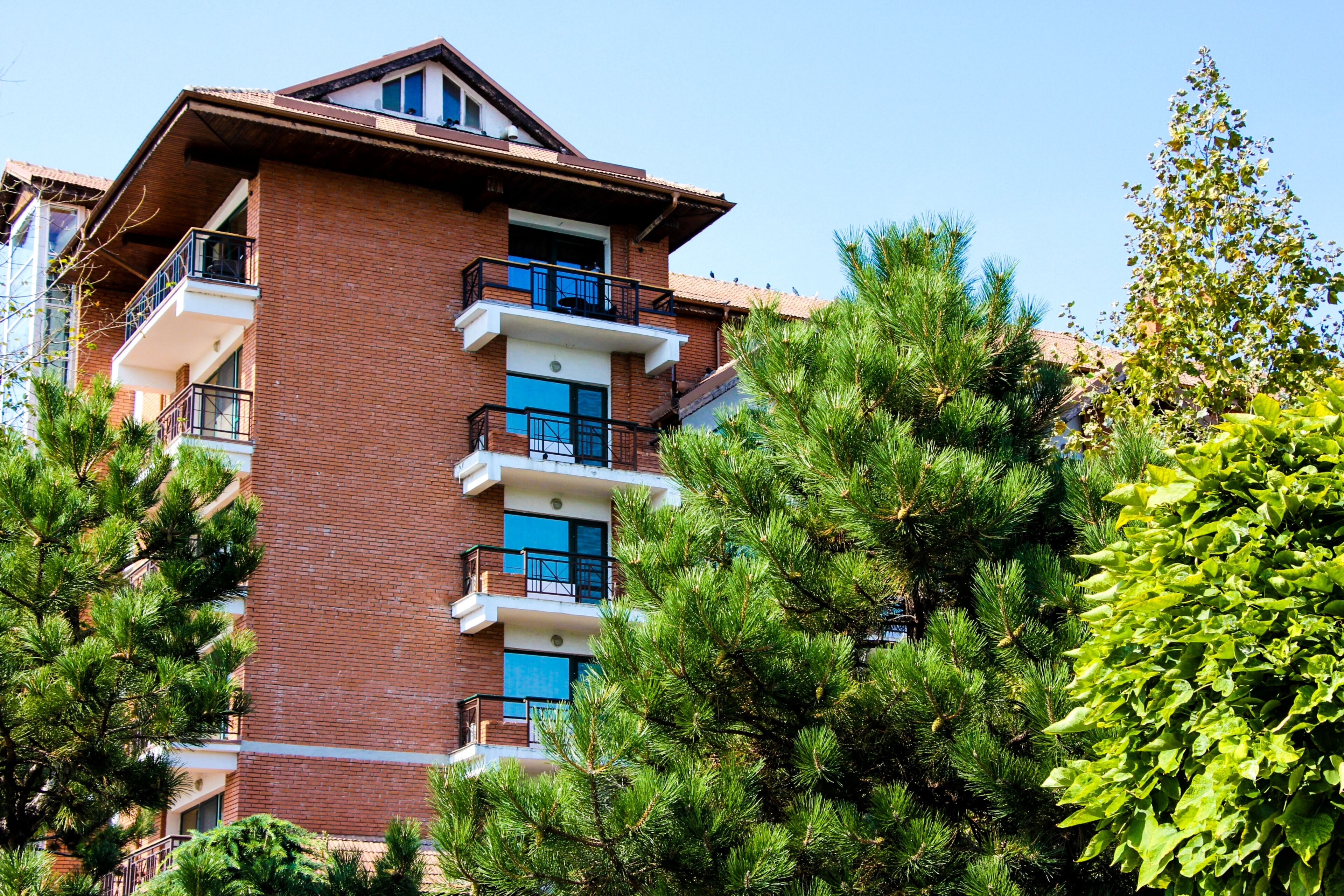 A multi-story building with balconies, surrounded by lush greenery.