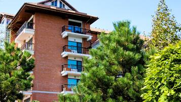A multi-story building with balconies, surrounded by lush greenery.