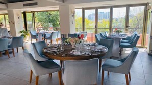 Comedor con mesas redondas dispuestas para cuatro personas, rodeado de sillas azules.