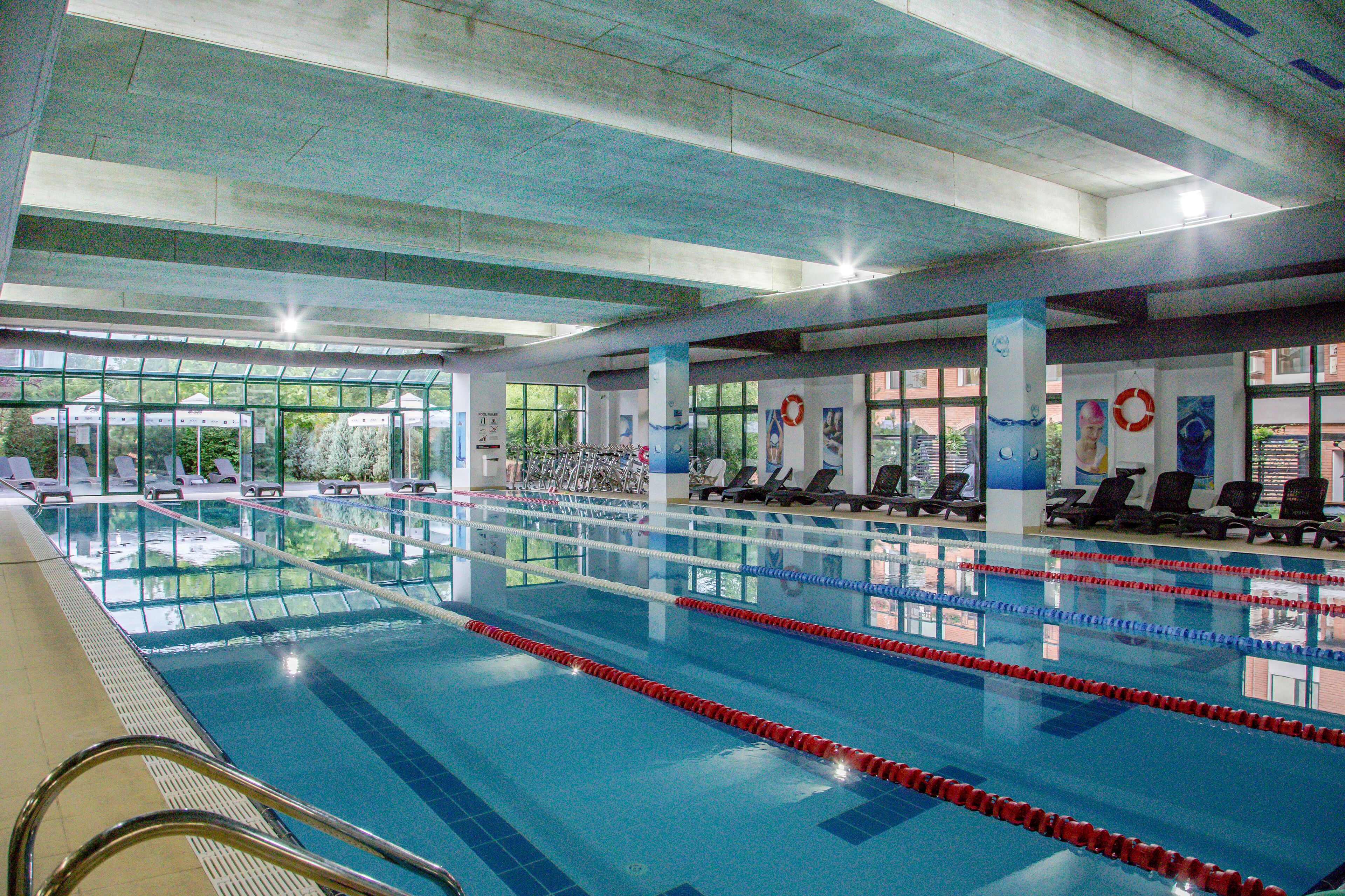 Una piscina cubierta, sombrillas, tumbonas