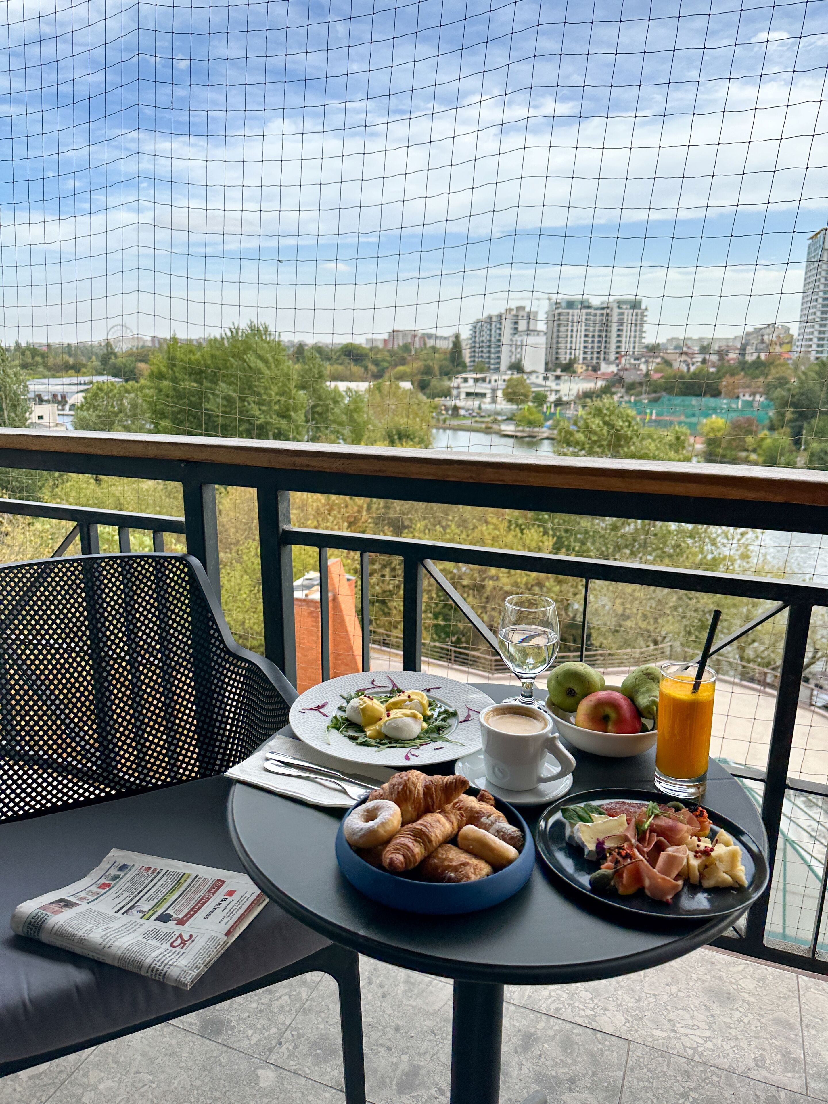 Ein Balkon mit einem Tisch, gedeckt für das Frühstück, darunter Croissants, Eier und Obst.