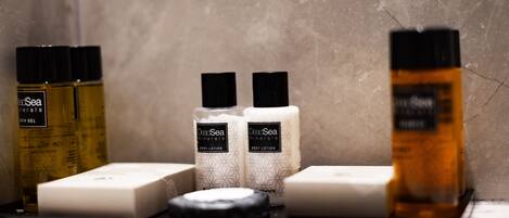 Un estante de baño con diversos artículos de aseo, incluyendo botellas de loción corporal, una pastilla de jabón y un frasco de gel de baño.