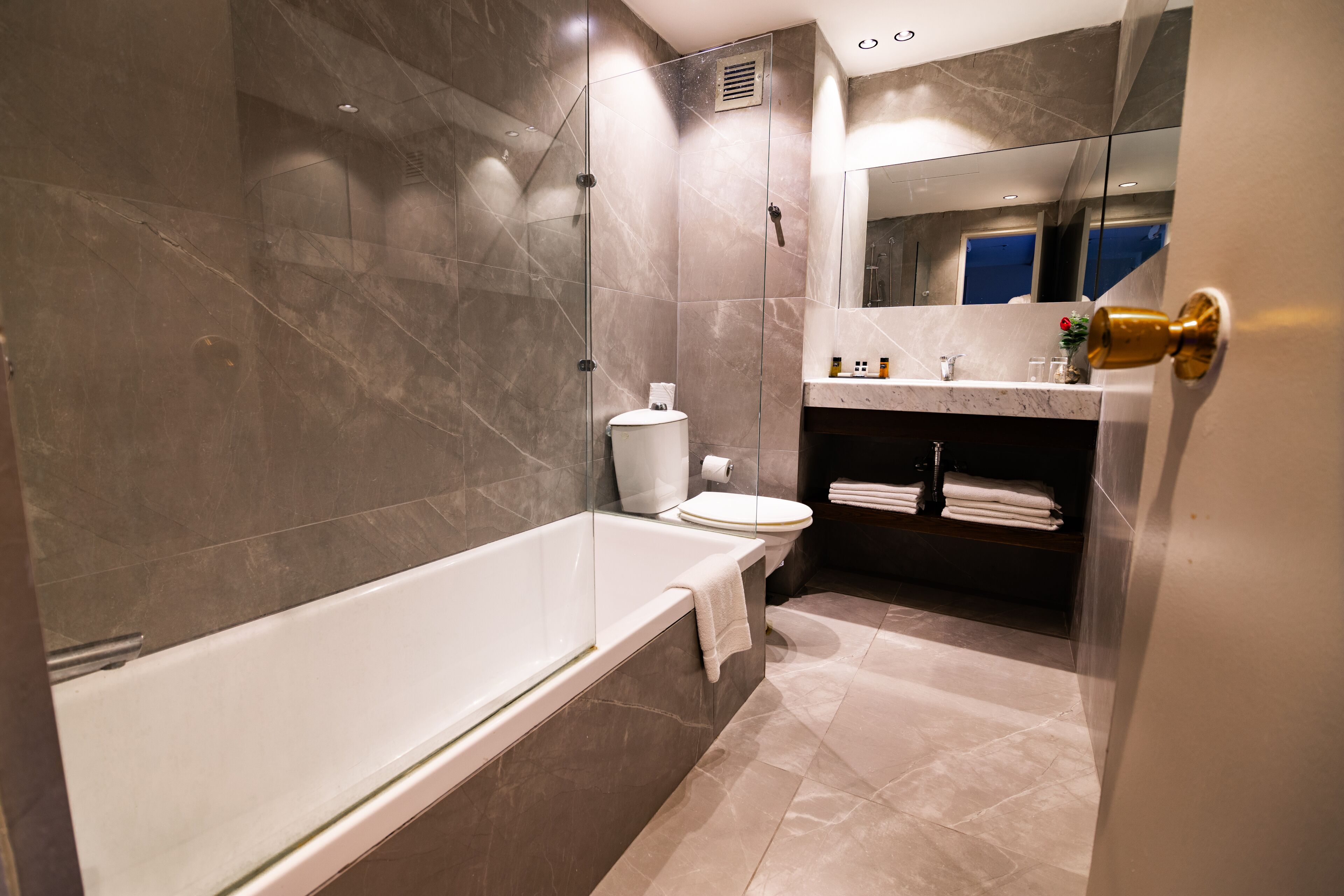 A modern bathroom with a glass-enclosed shower, a white bathtub, and a toilet.