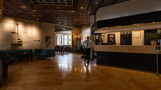 A modern lobby with a reception desk, seating area, and a view of the dining area. - Lev Yerushalayim (Jerusalem)