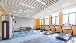 Une salle de sport équipée de tapis de course, de vélos elliptiques et d’un support pour les exercices de squat.