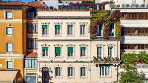 A multi-story building with a series of windows, some with shutters, and balconies with potted plants. - The B Place Hotel (Rome)