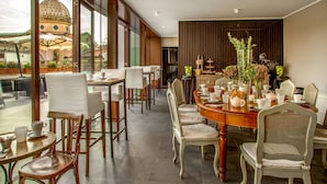 A dining area with a large round table, multiple chairs, and a view of a historic building through large windows.